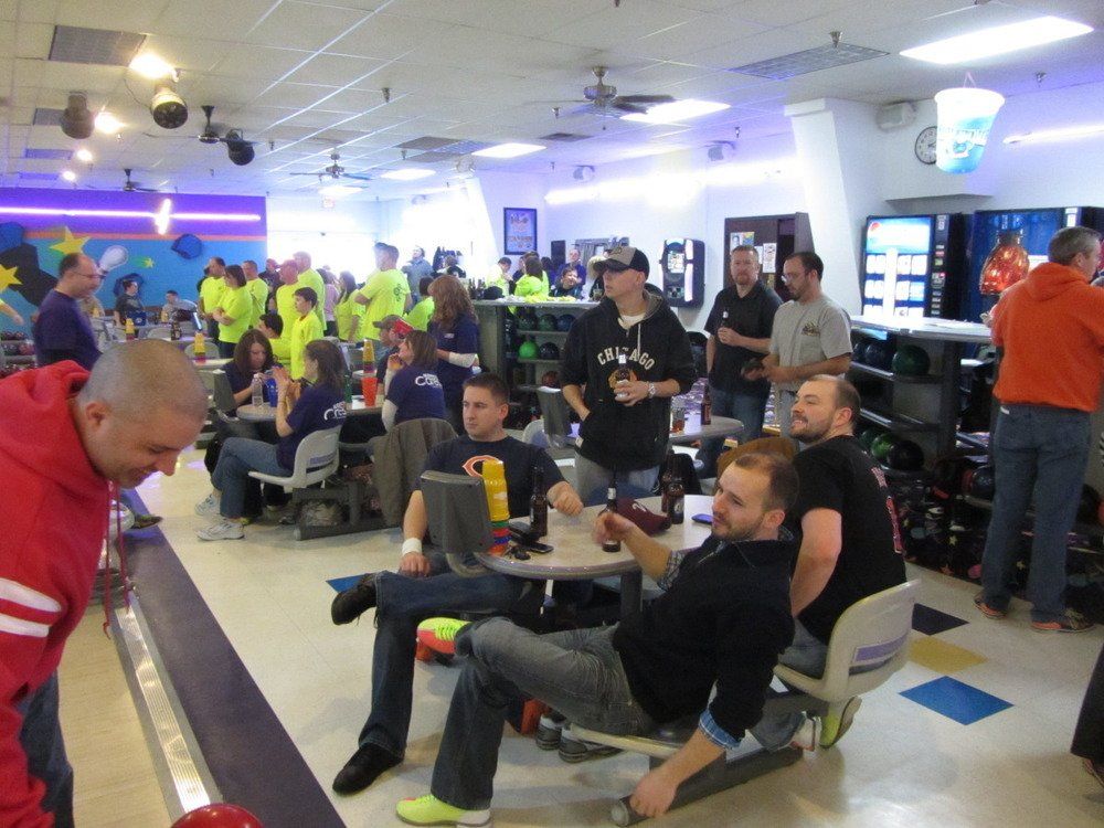 A man in a red jacket is bowling in a bowling alley