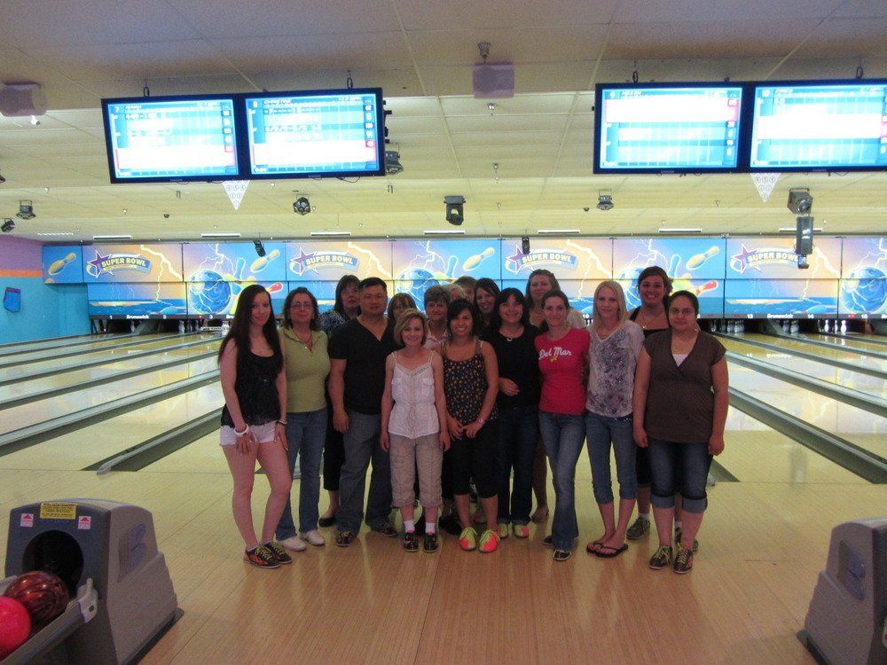 A group of people are posing for a picture in a bowling alley