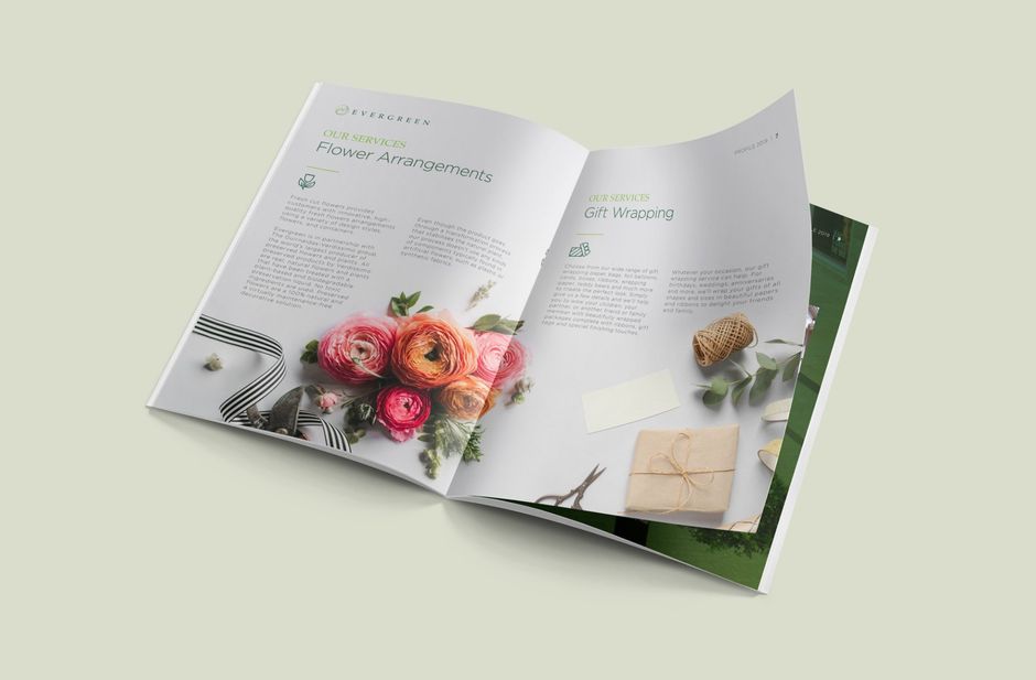 Open magazine with floral arrangement and gift on pages.