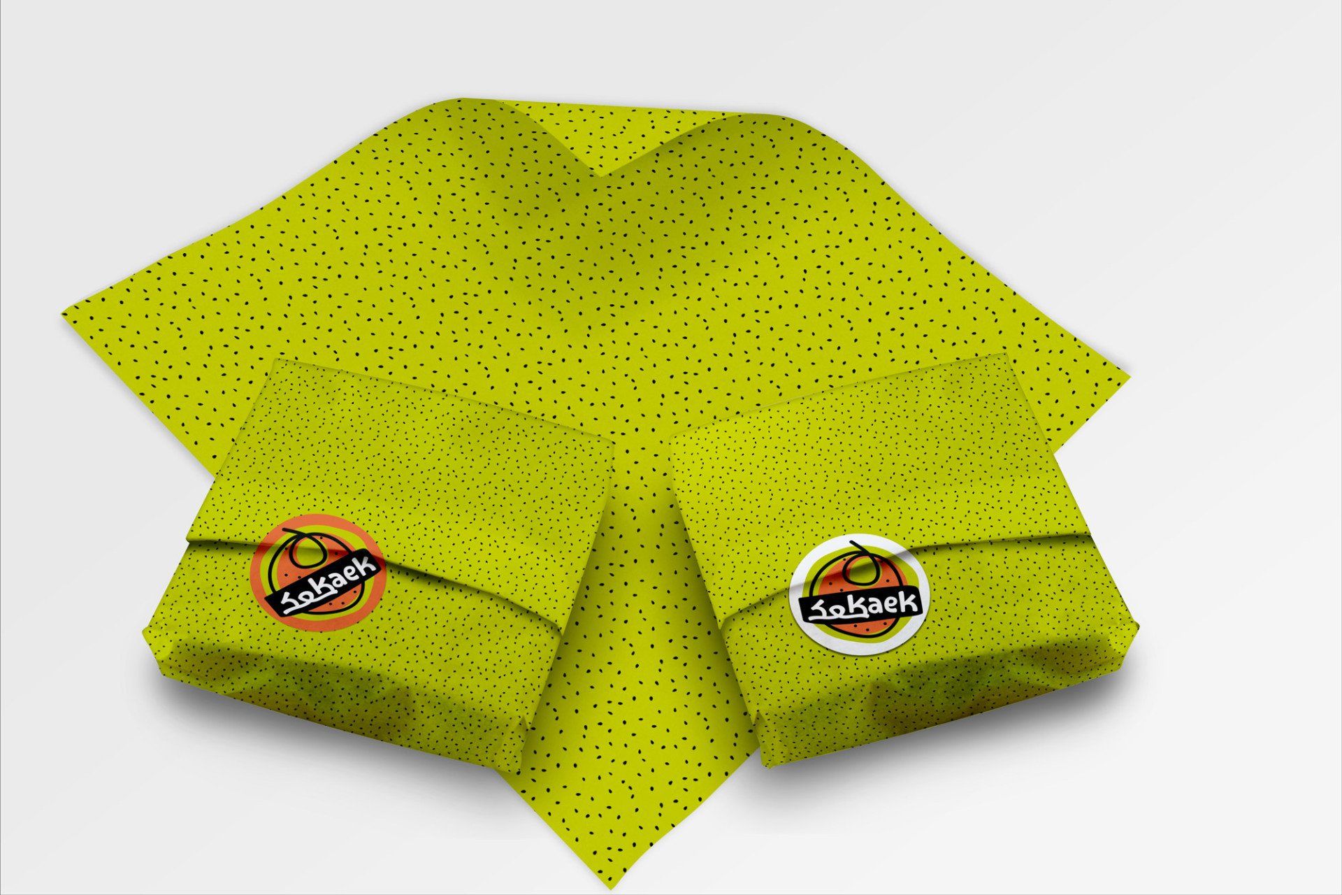 Two wrapped packages on green polka-dotted paper with circular orange and black labels; placed on a white surface.