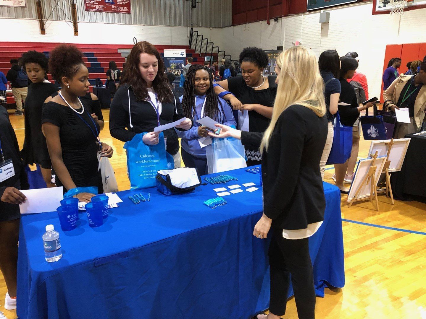 A group of people are standing around a table at a job fair.