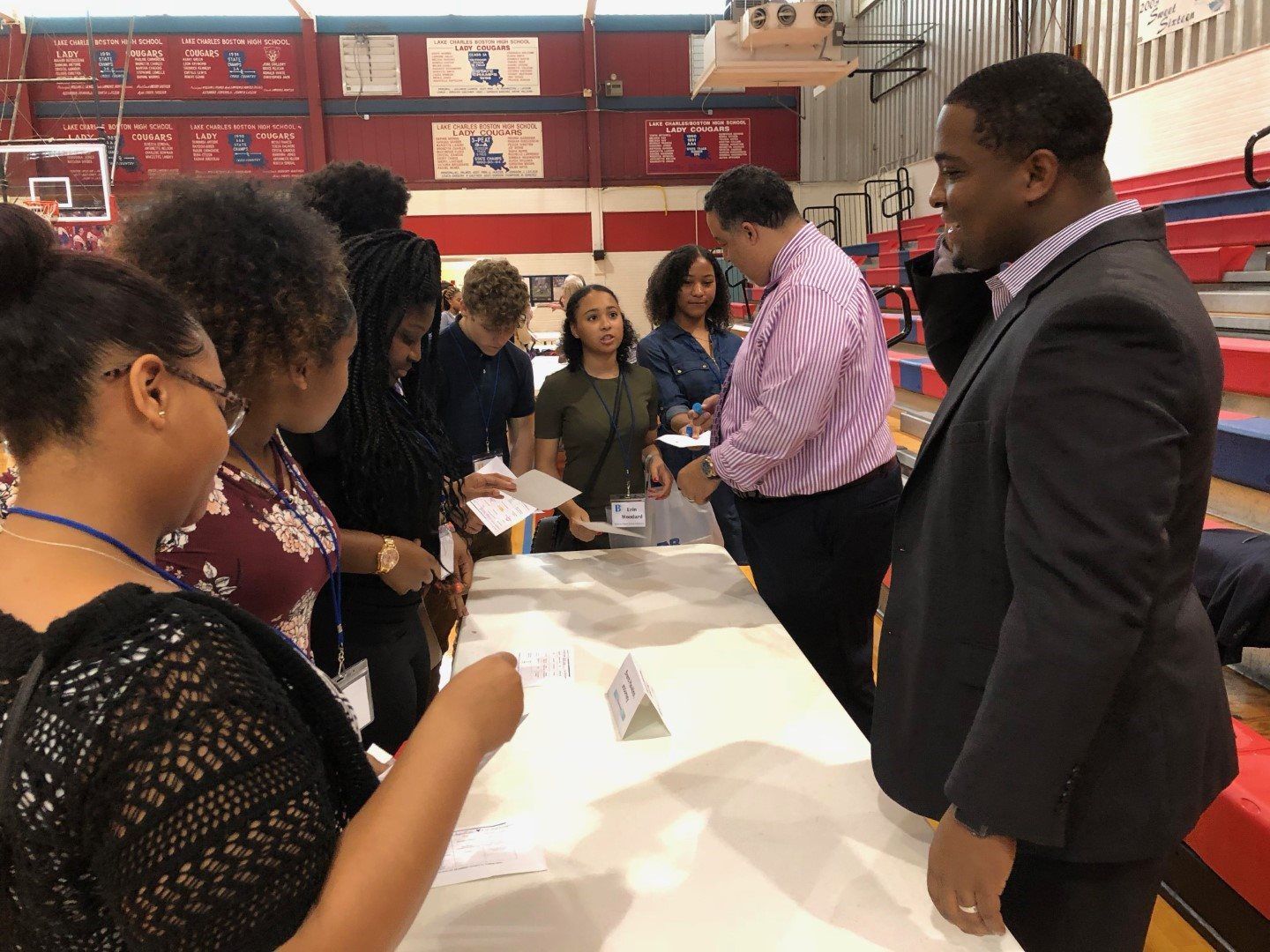 A group of people are standing around a table in a gym.