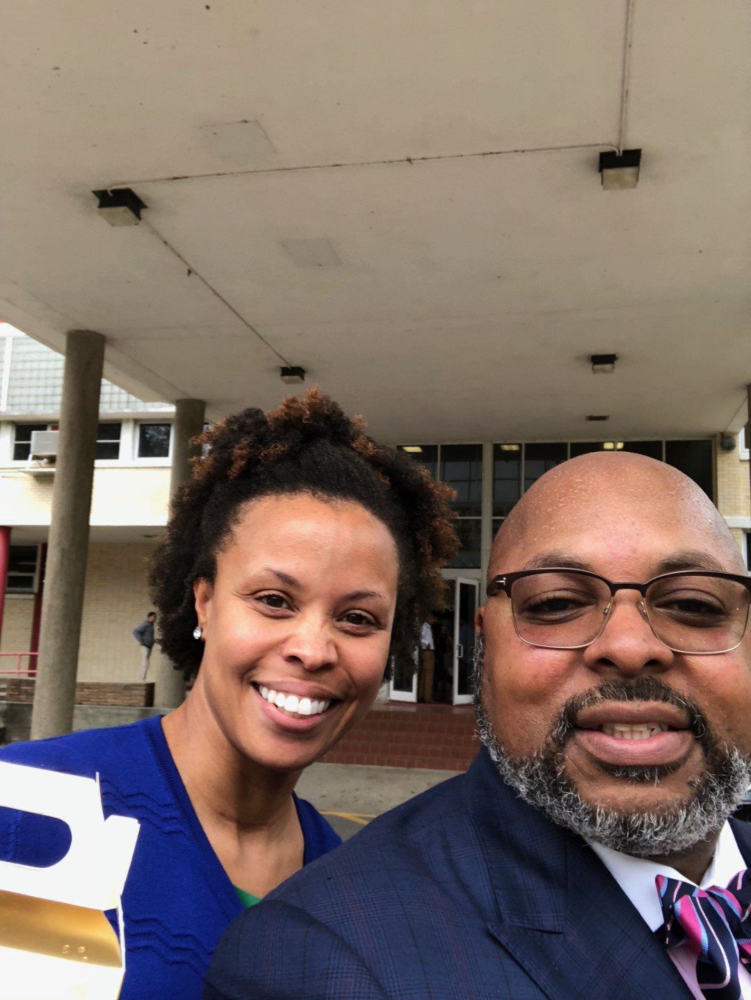 A man and a woman are posing for a picture in front of a building.