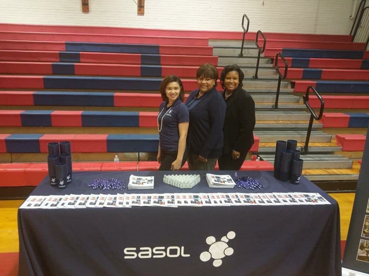 Three women standing in front of a table that says sasol