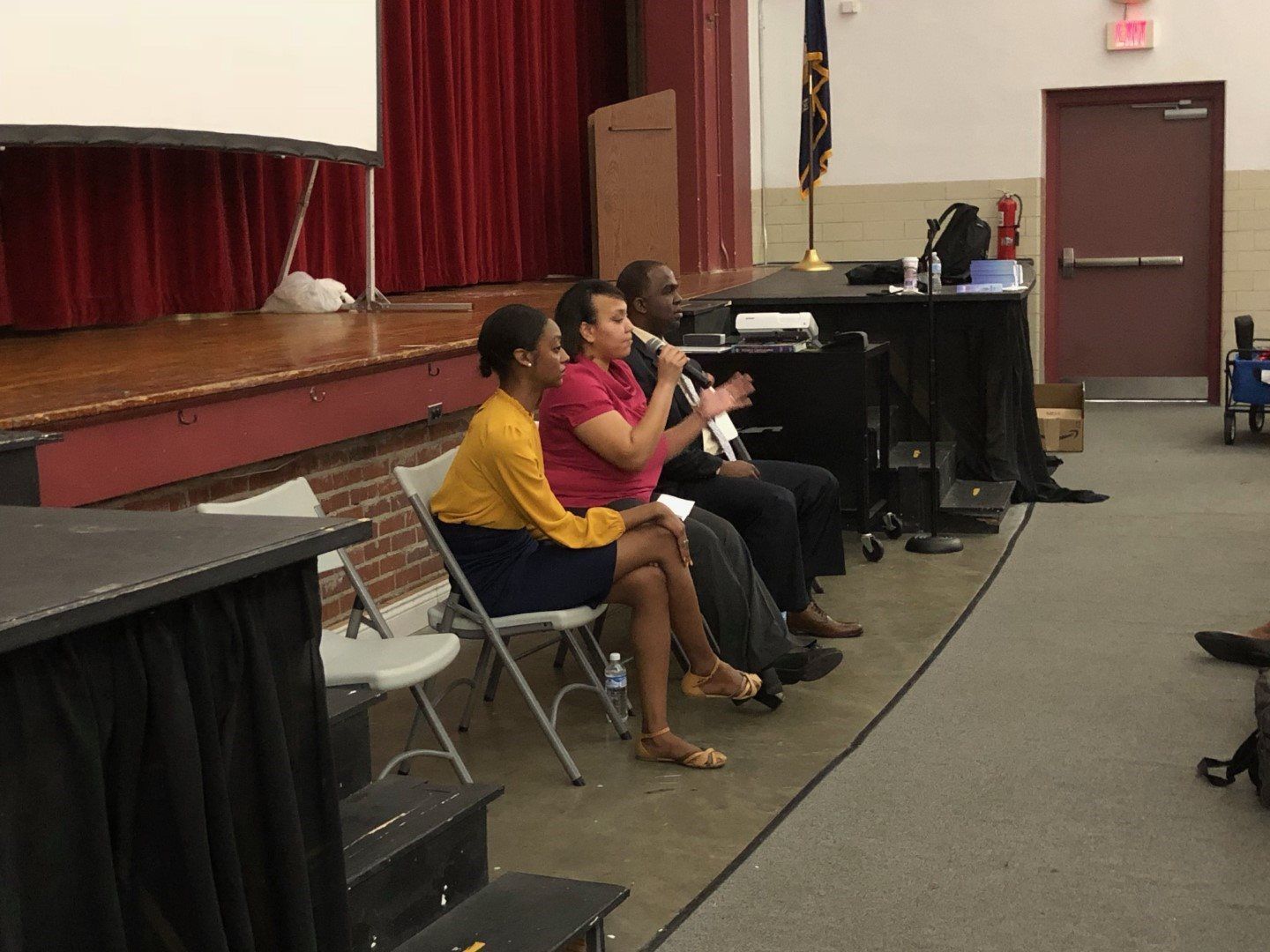 A group of people are sitting in chairs in front of a stage.