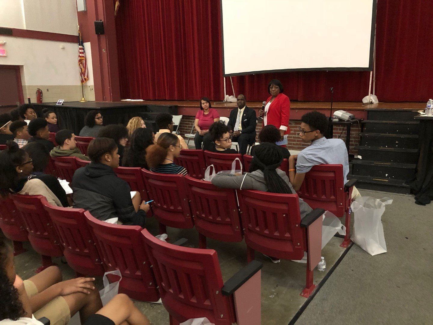 A group of people are sitting in an auditorium watching a presentation