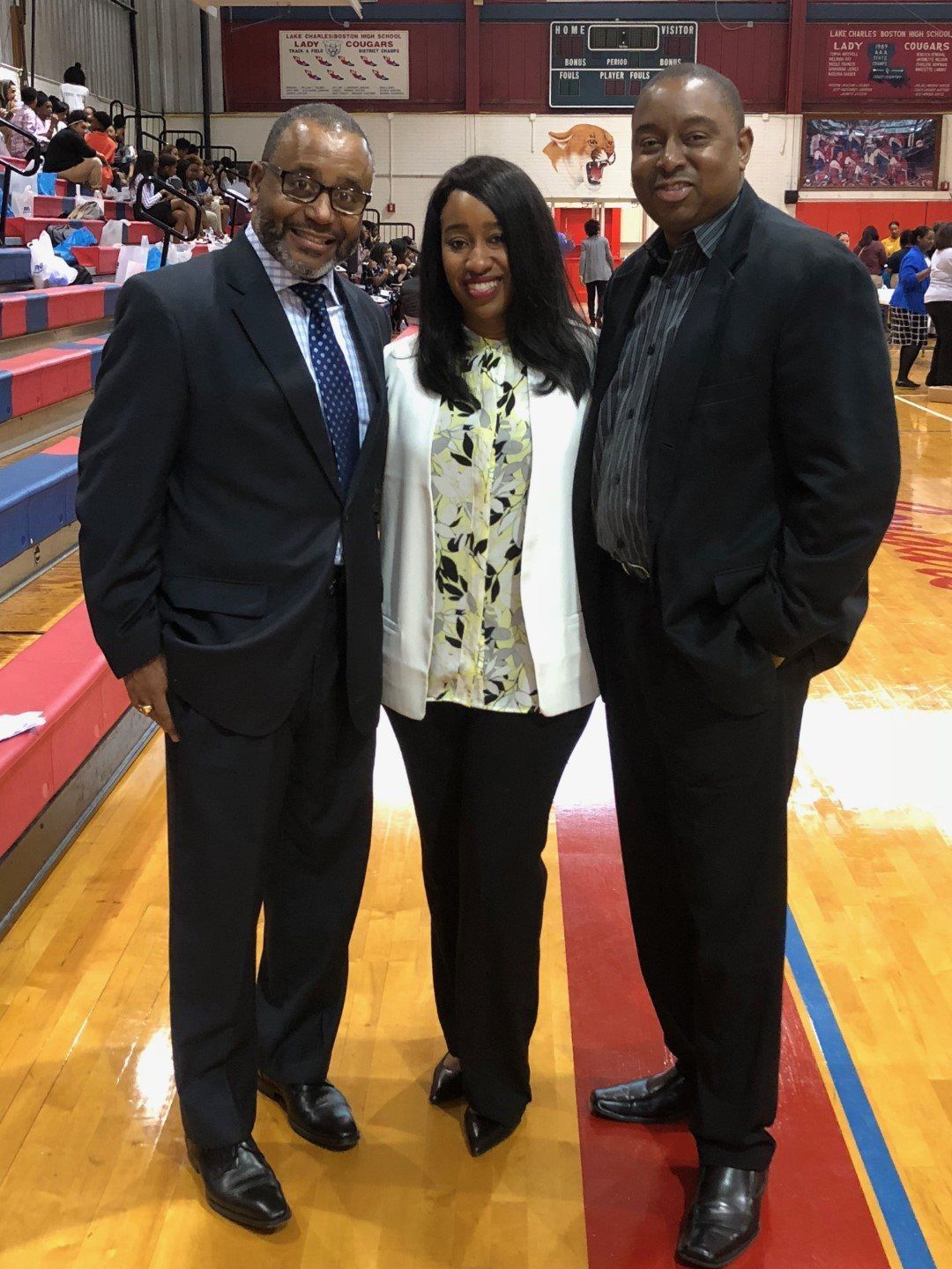 Three people are posing for a picture on a basketball court
