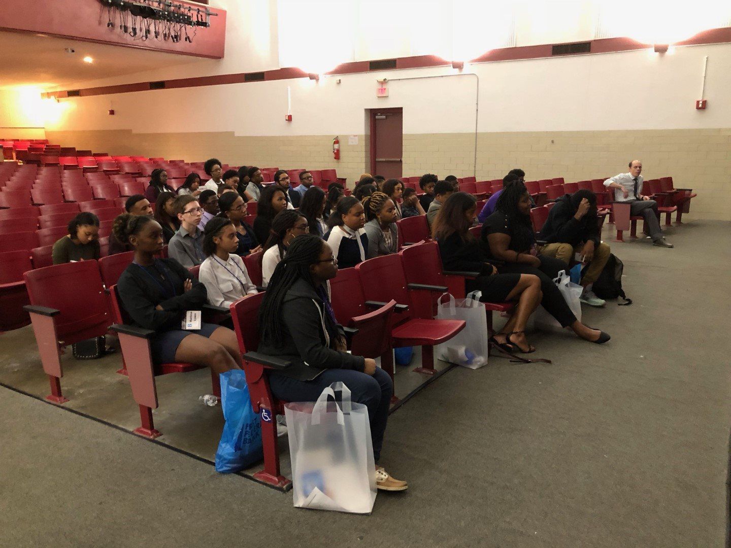 A group of people are sitting in an auditorium watching a presentation.