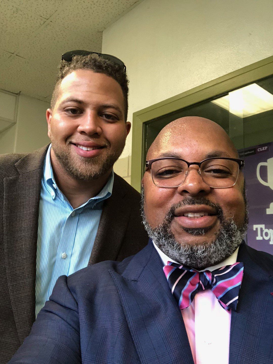 Two men in suits and bow ties are posing for a picture.