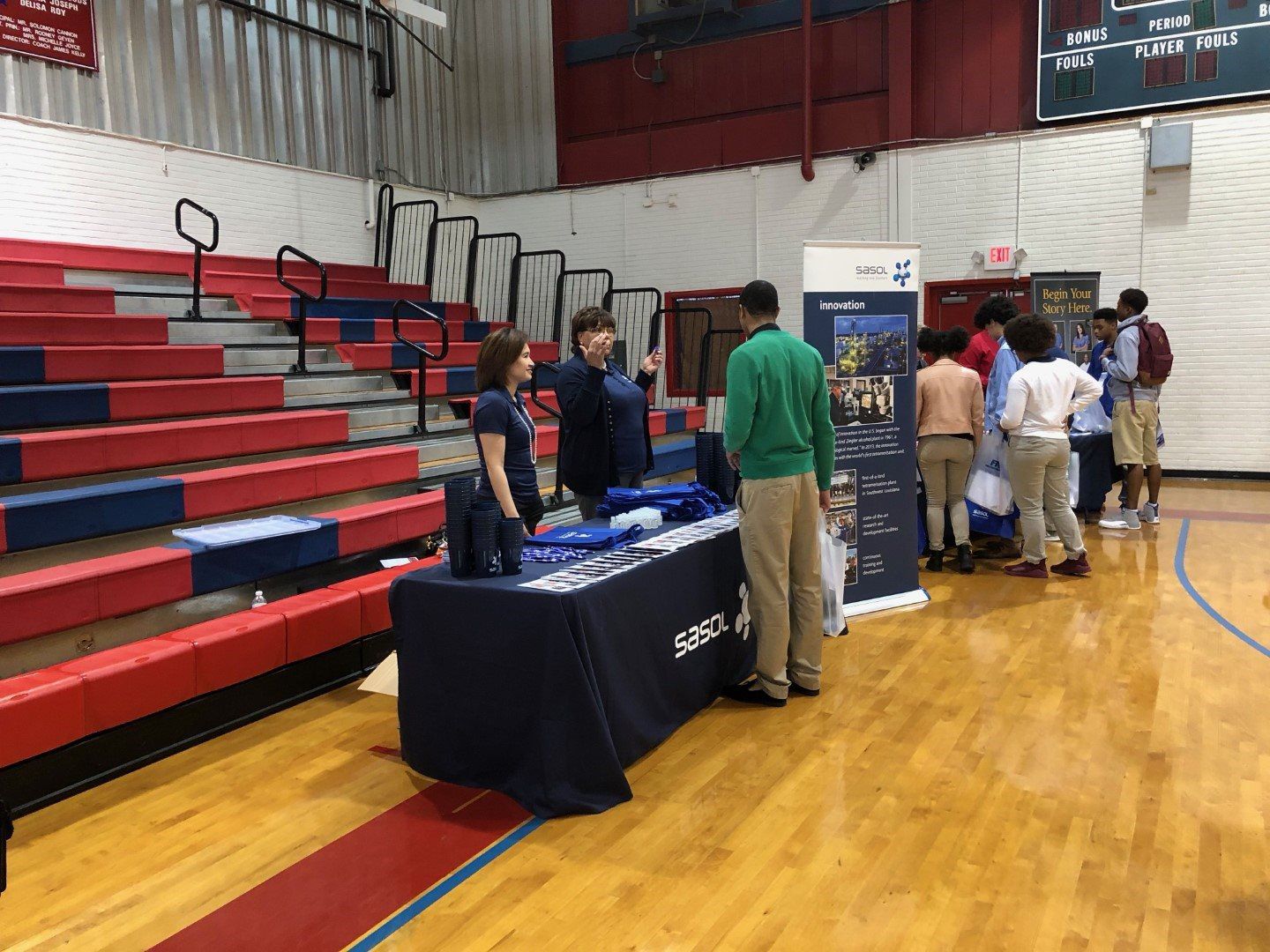 A group of people are standing around a table in a gym.