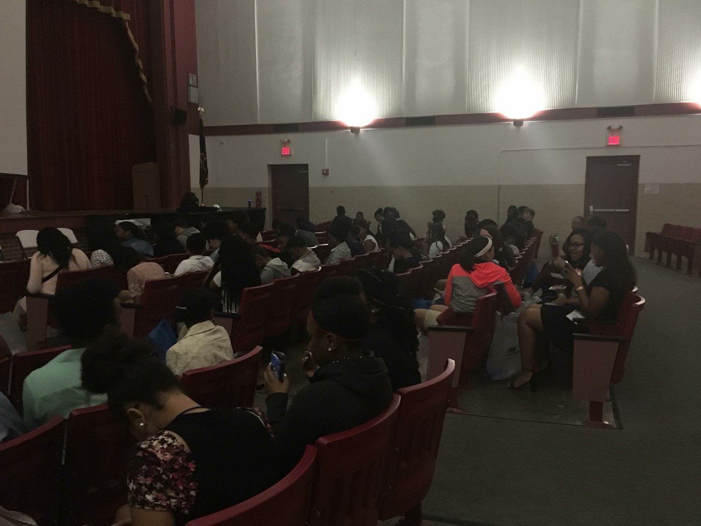 A large group of people are sitting in a dark auditorium