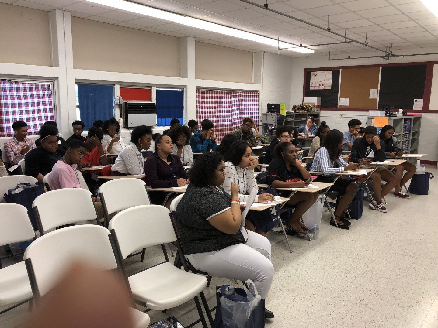 A group of people are sitting at desks in a classroom.