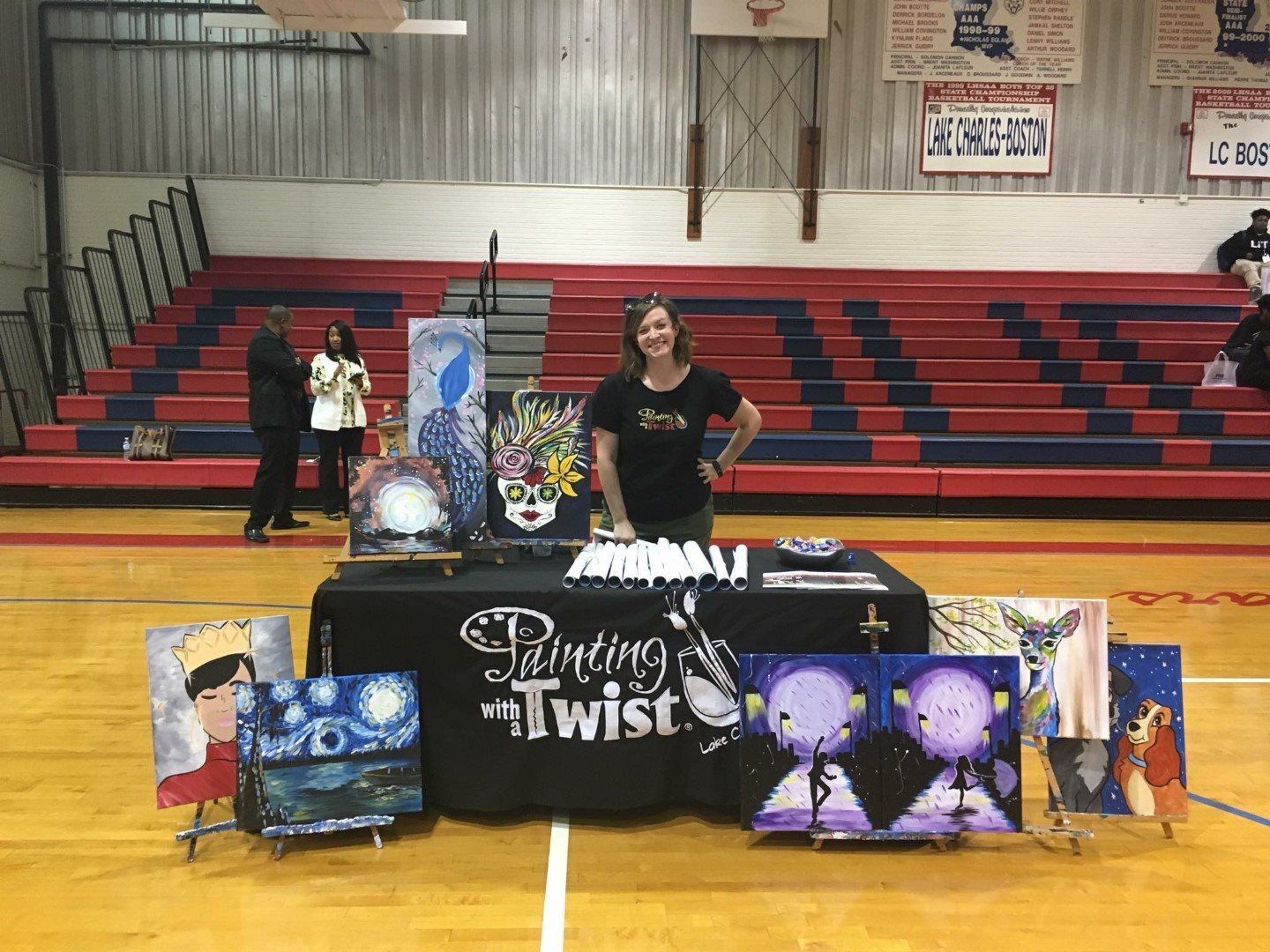 A woman is standing in front of a table with paintings on it.