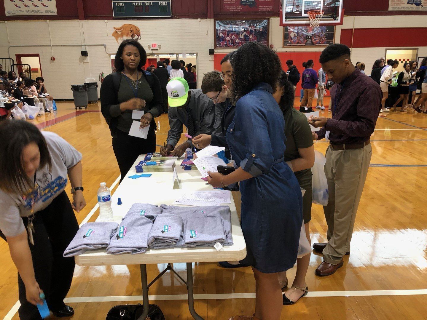 A group of people are standing around a table in a gym.