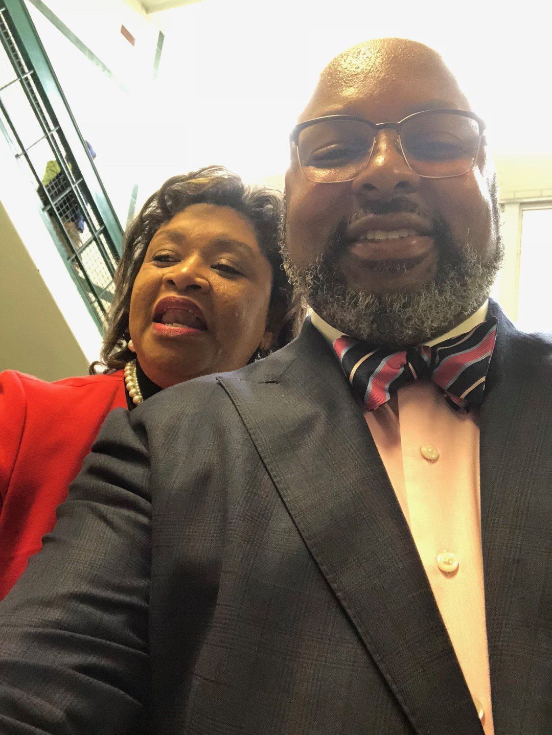A man in a suit and bow tie is standing next to a woman in a red jacket