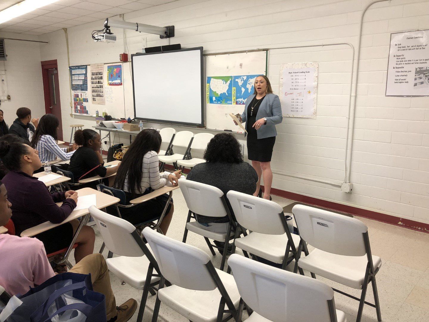 A woman is giving a presentation to a group of people in a classroom.