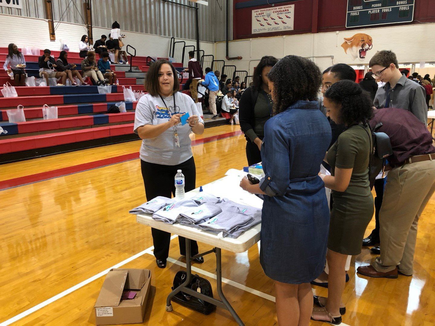A group of people are standing around a table in a gym.