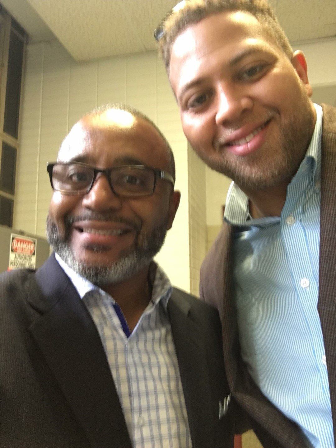 Two men posing for a picture with one wearing glasses