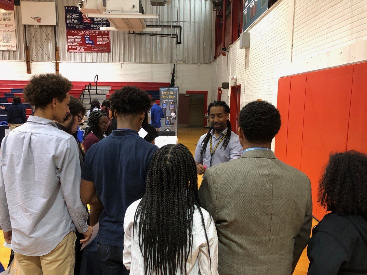 A group of people are standing in a gym talking to each other.