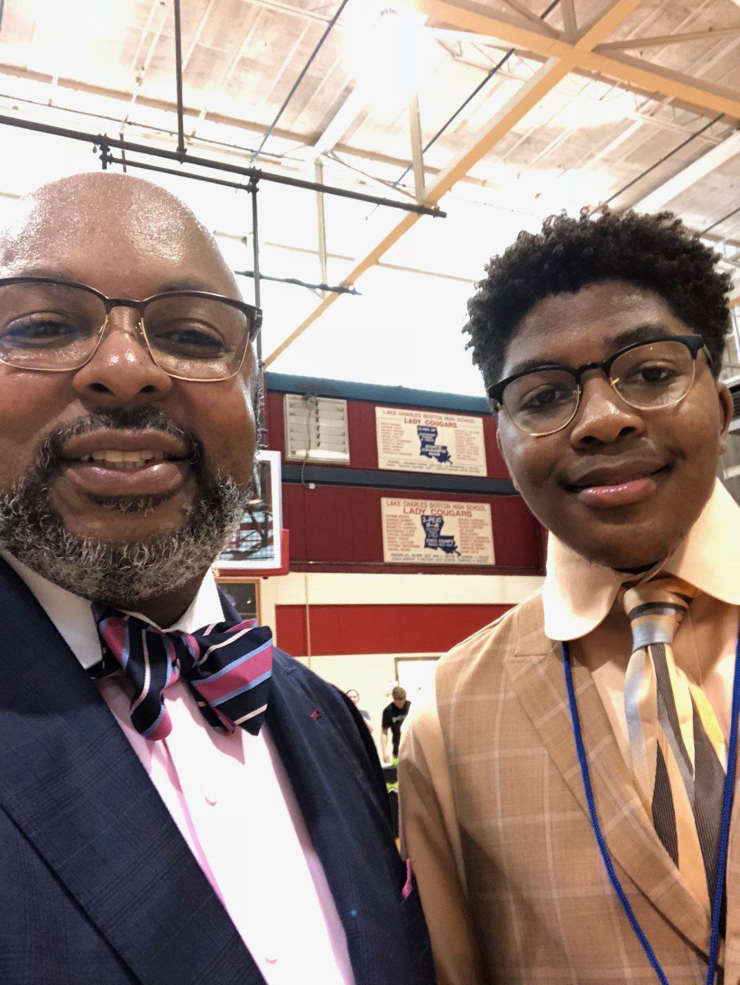 A man in a suit and tie is standing next to a boy in a bow tie.