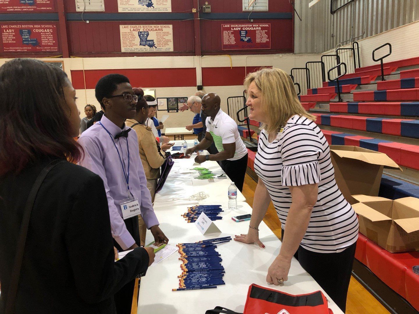 A group of people are standing around a table in a gym.