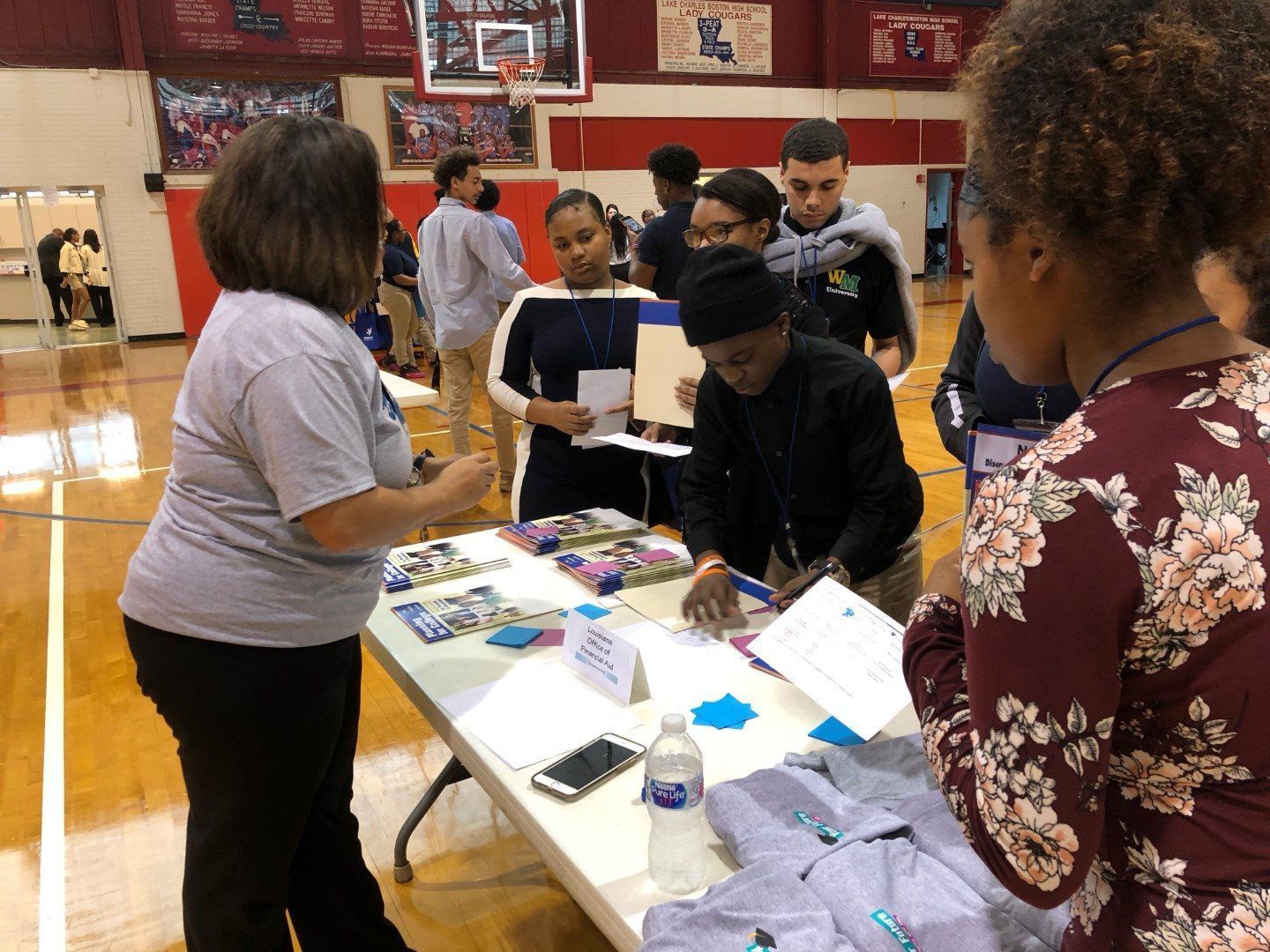 A group of people are standing around a table in a gym.
