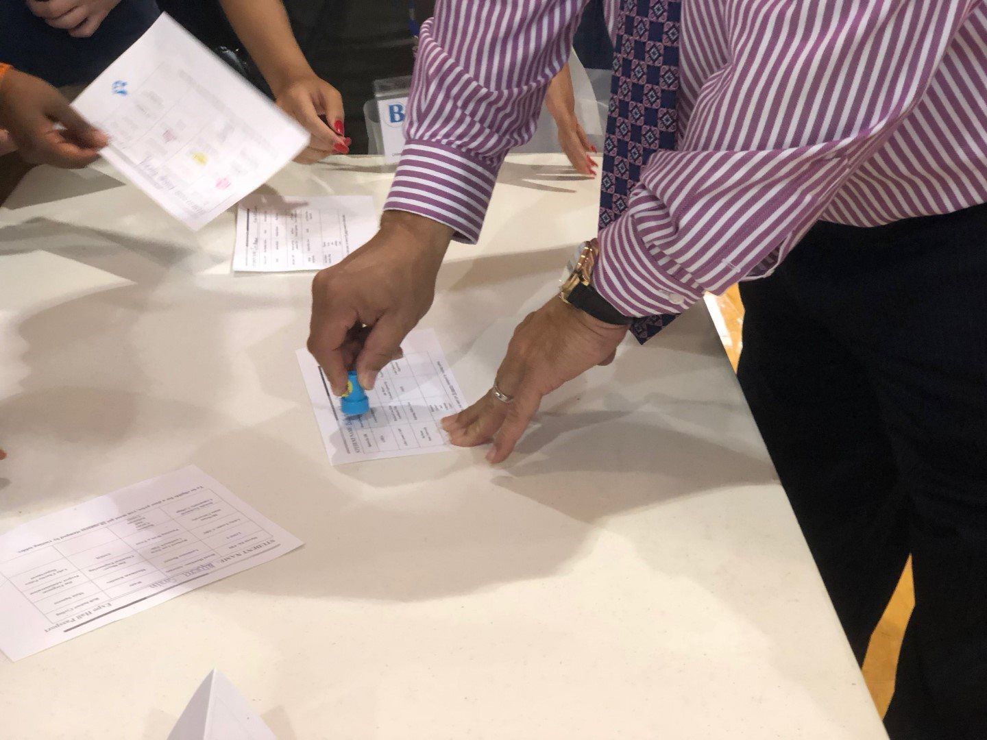 A man in a striped shirt is stamping a piece of paper