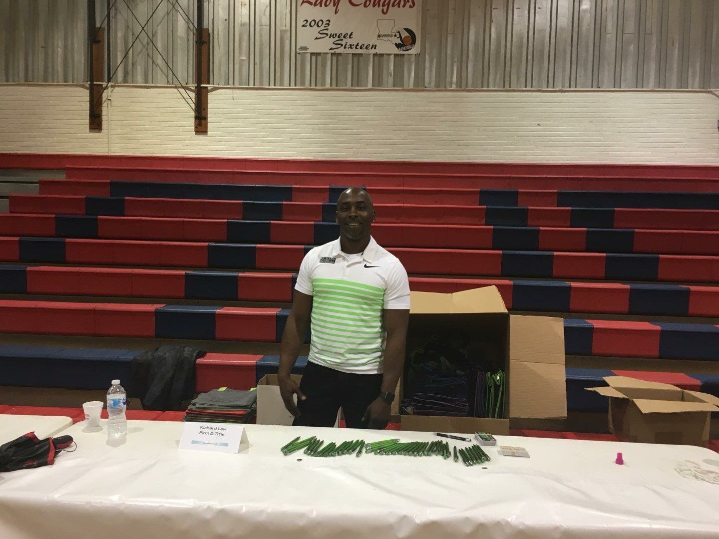 A man is standing in front of a table in a gym.