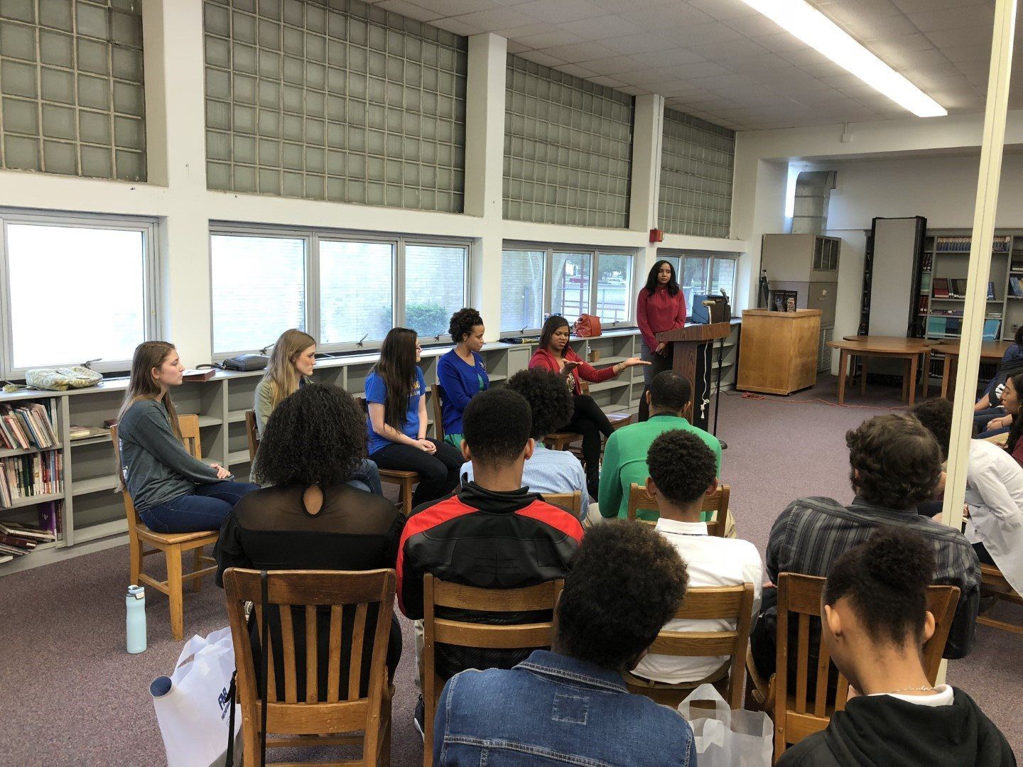 A group of people are sitting in chairs in a library.
