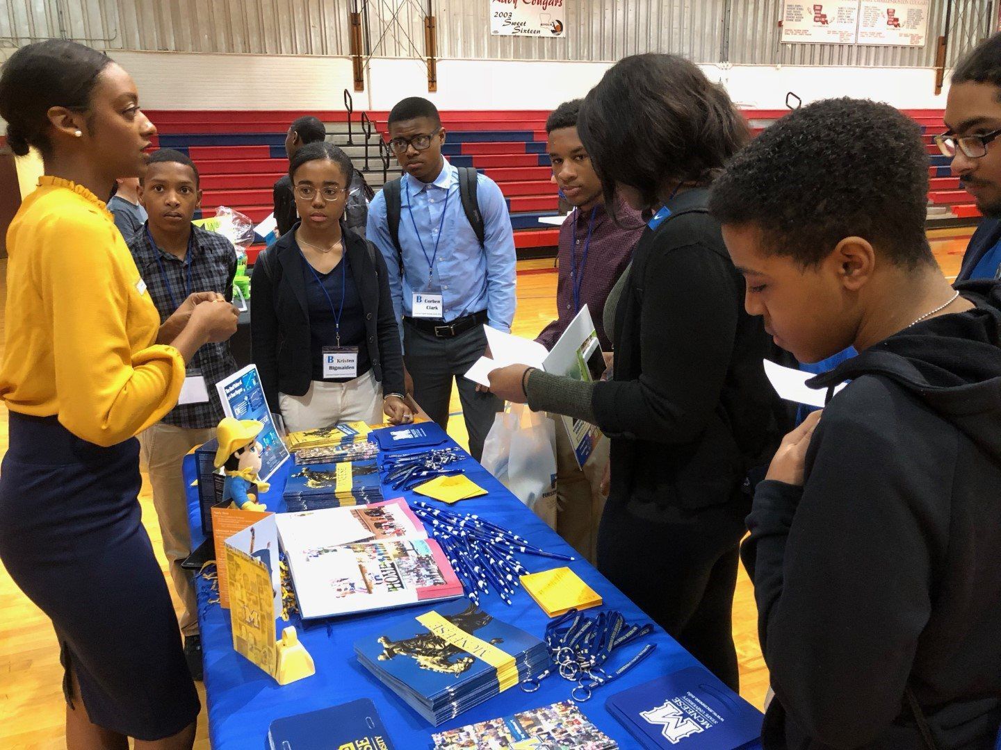 A group of people are standing around a table in a gym.