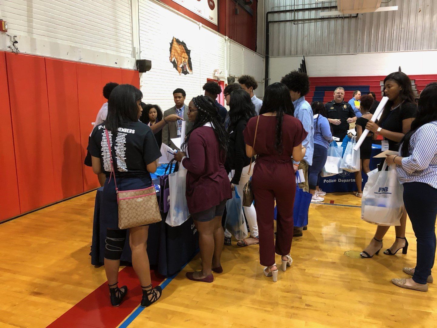 A group of people are standing around a table in a gym.