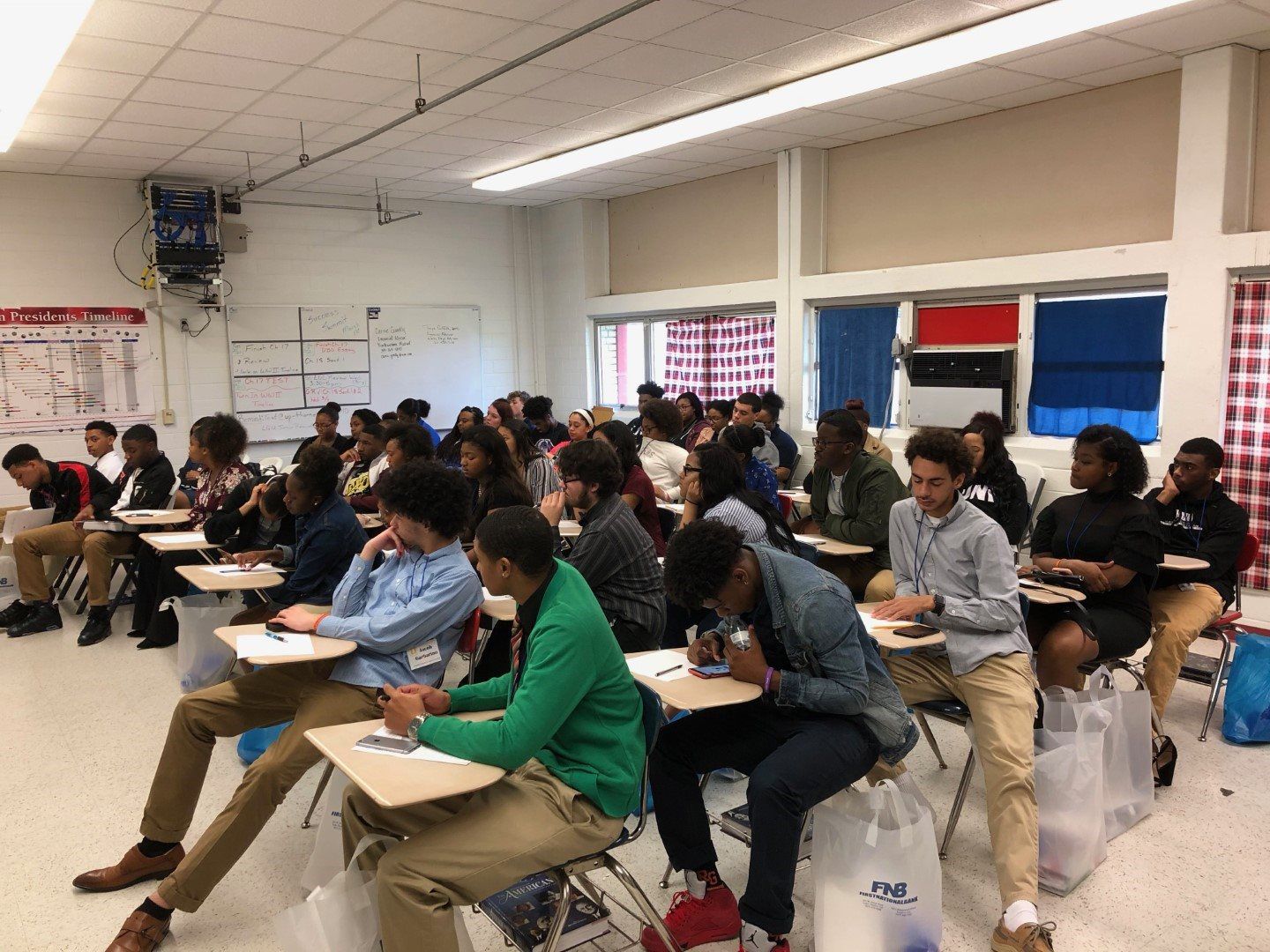 A large group of people are sitting at desks in a classroom.