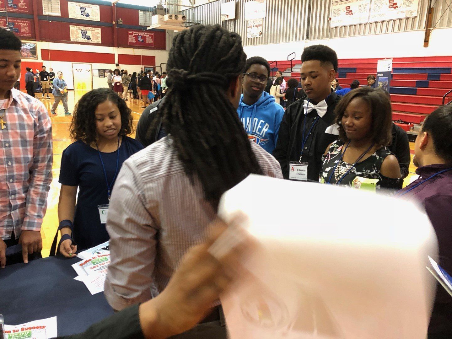 A group of young people are standing around a table in a gym.