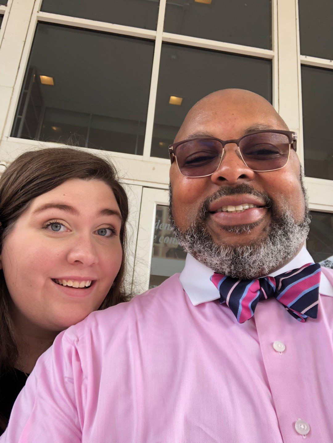 A man in a pink shirt and bow tie is posing for a picture with a woman.