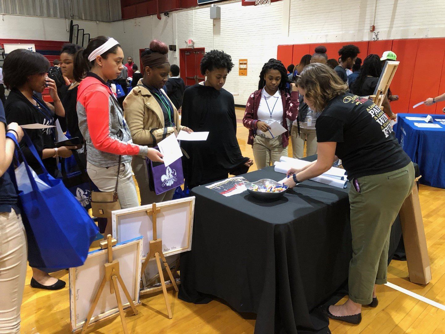 A group of people are standing around a table in a gym.