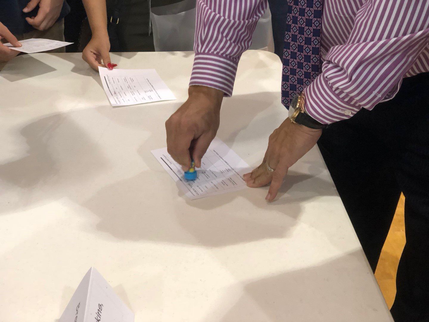 A man in a striped shirt and tie is stamping a piece of paper