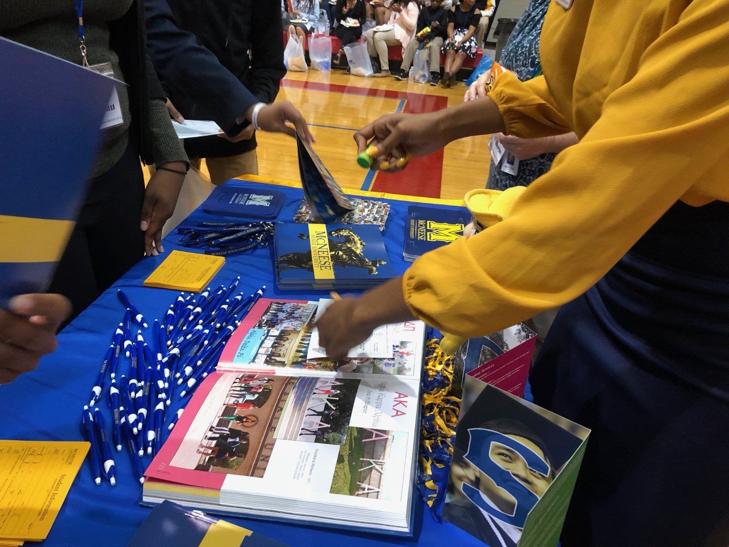A group of people are standing around a table with a book that says aca on it