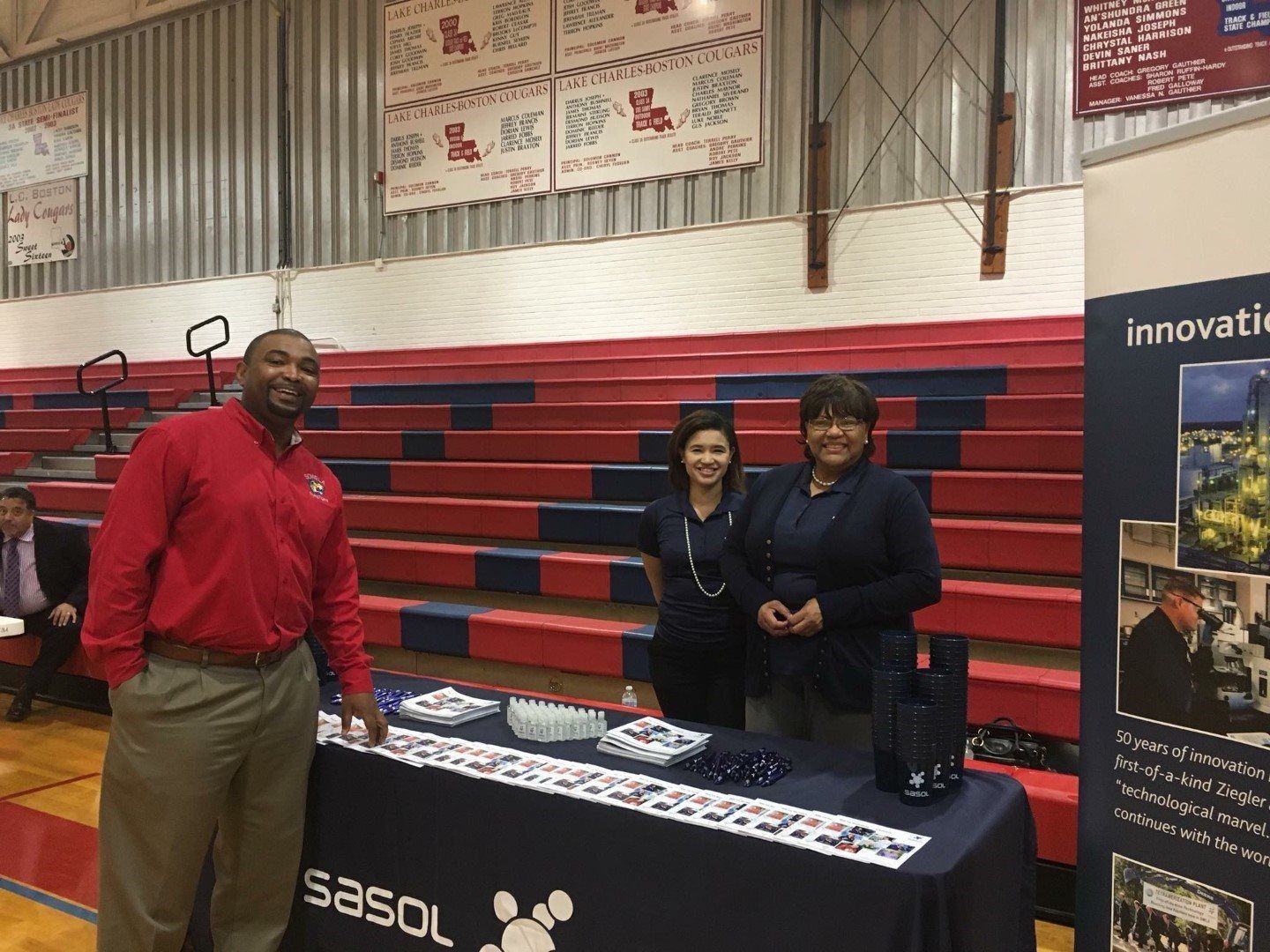 A group of people standing around a table that says sasol on it
