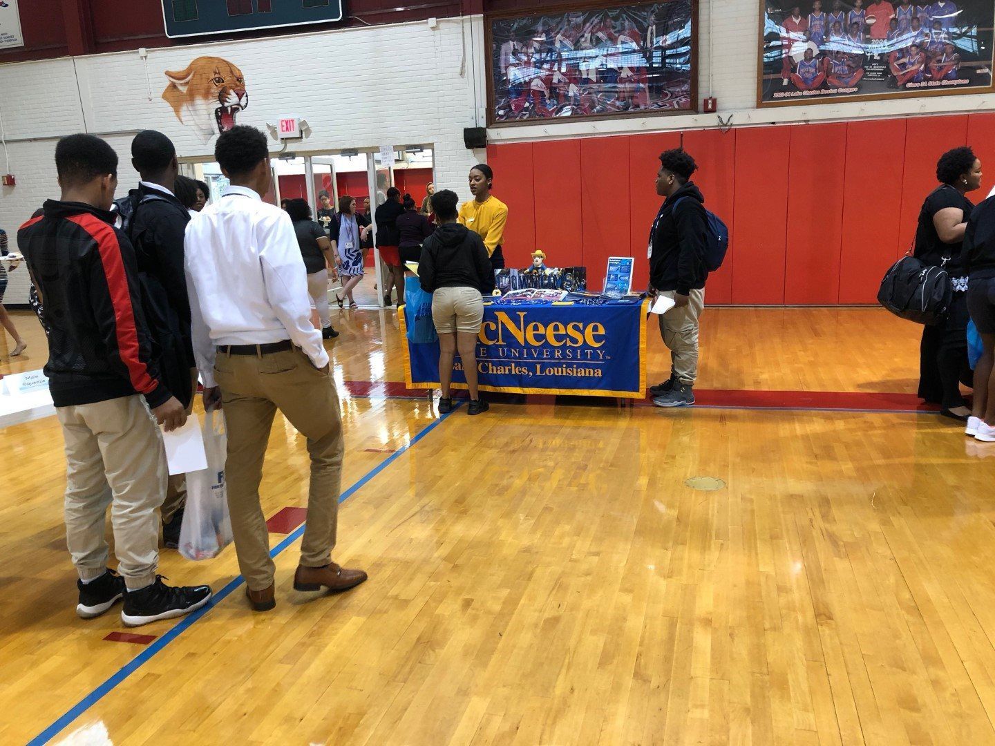 A group of people are standing around a table in a gym.