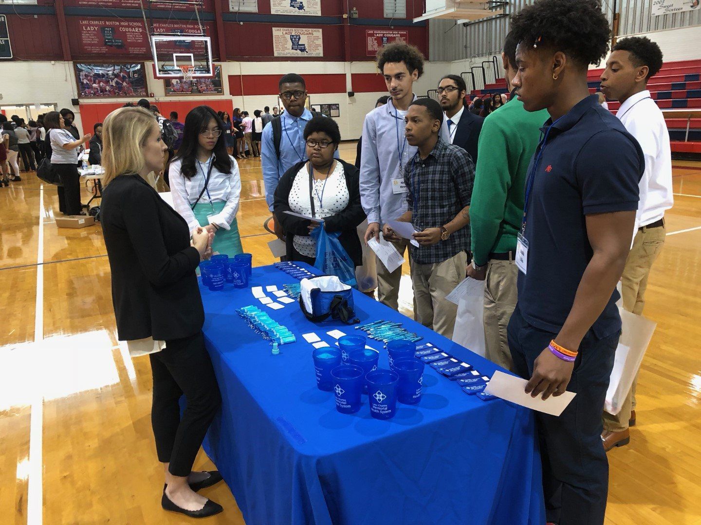 A group of people are standing around a table at a job fair.
