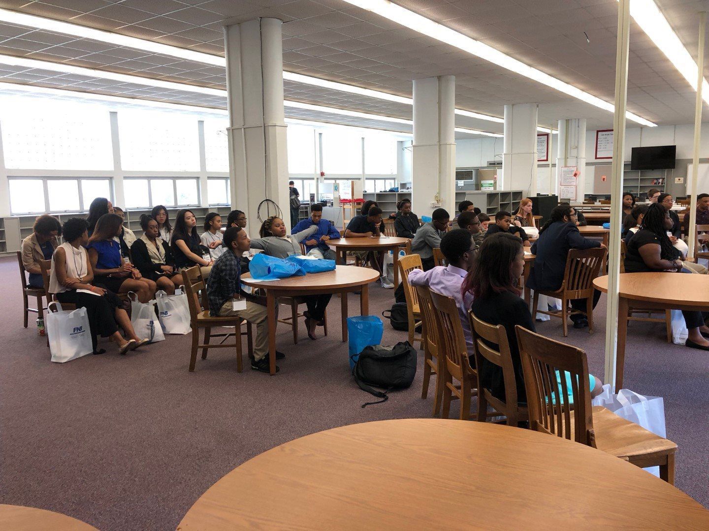 A group of people are sitting at tables in a library.