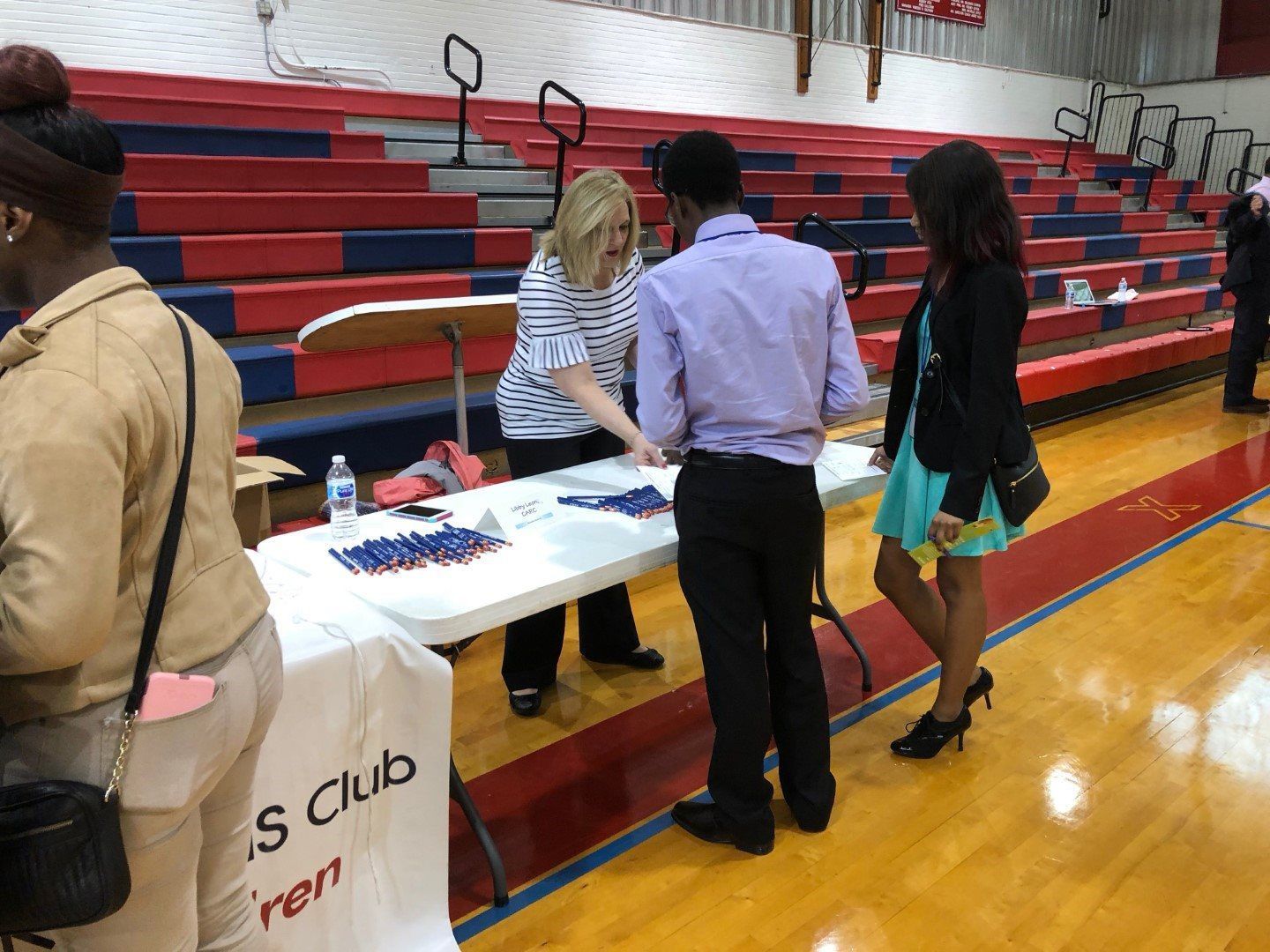A group of people are standing around a table in a gym.
