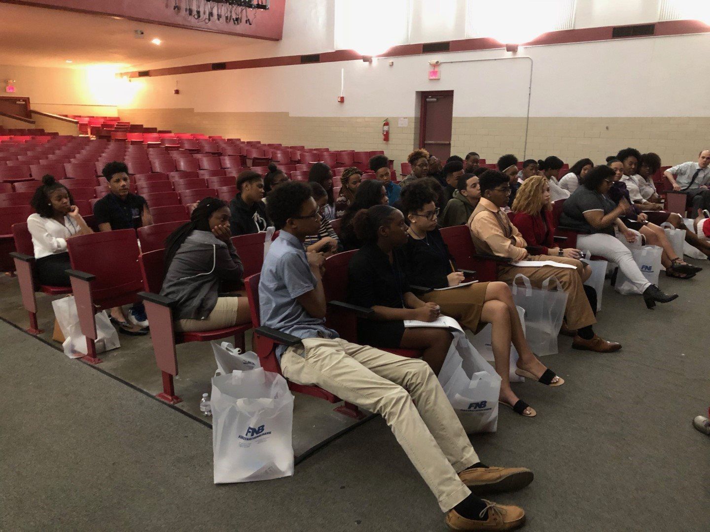 A group of people are sitting in an auditorium watching a presentation.