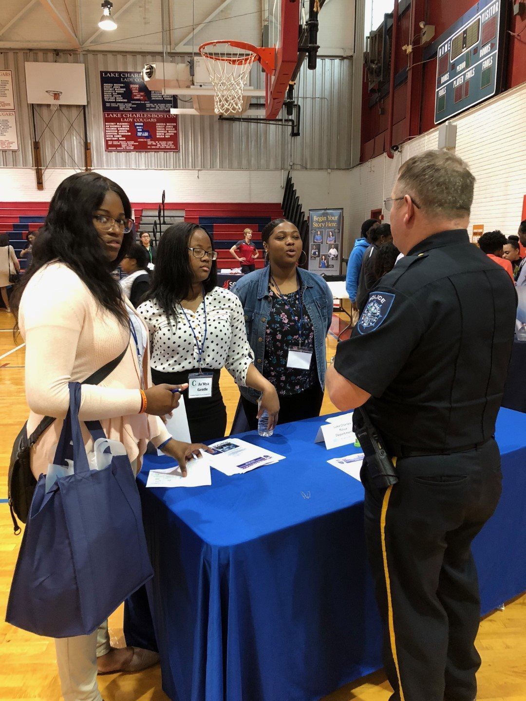 A group of people are standing around a table talking to a police officer.