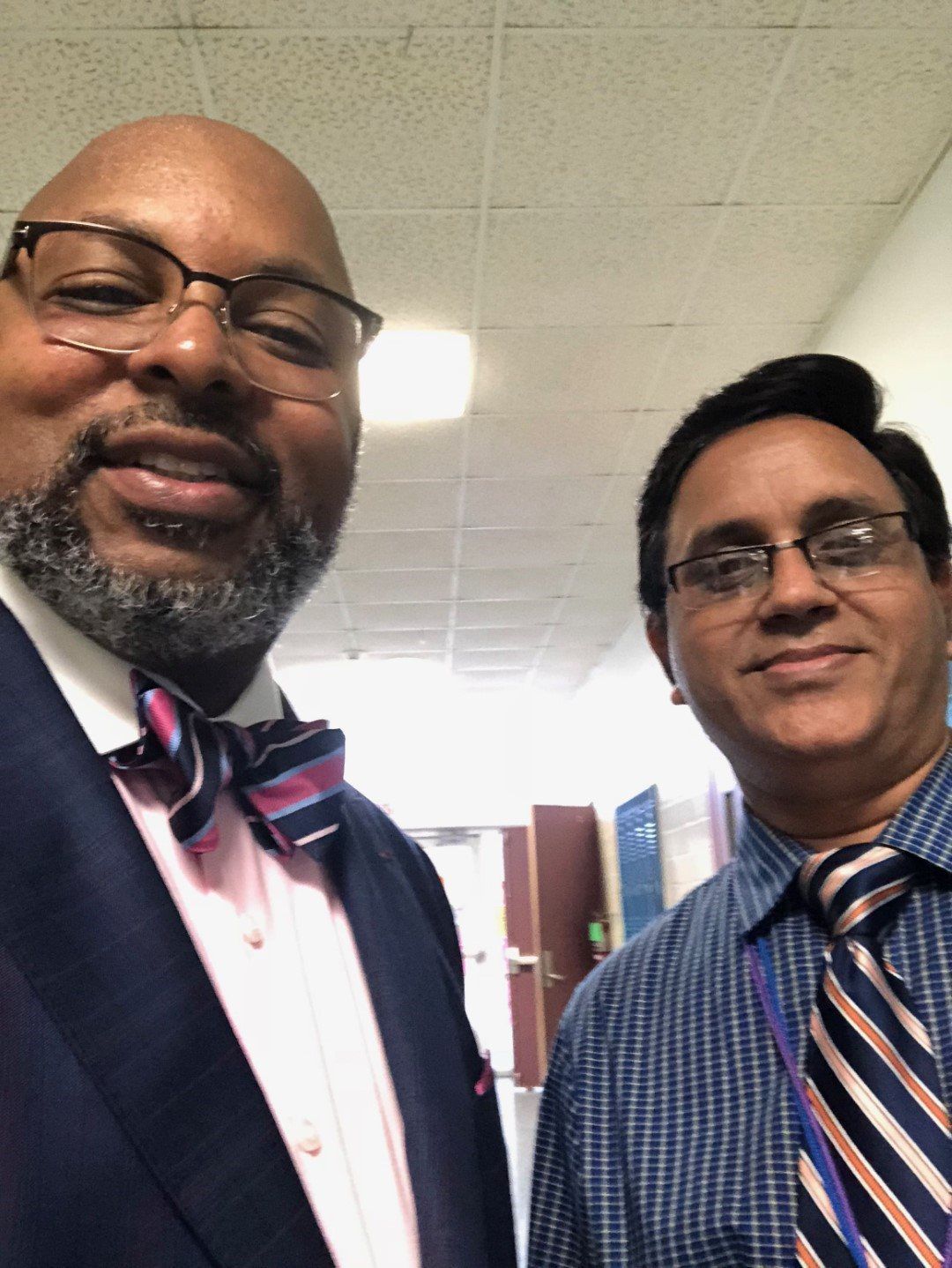 Two men in suits and ties pose for a picture