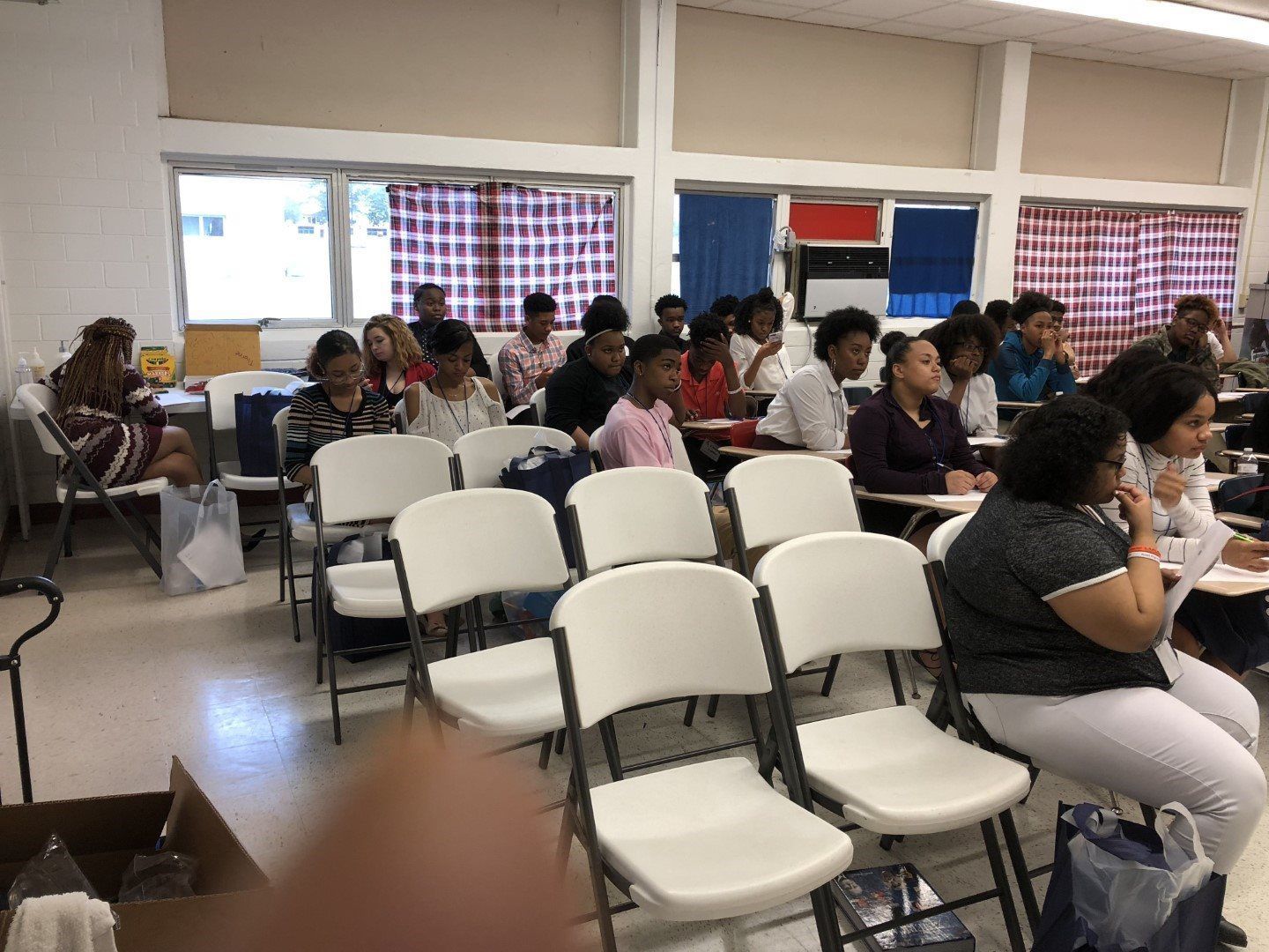 A group of people are sitting in white folding chairs in a room.
