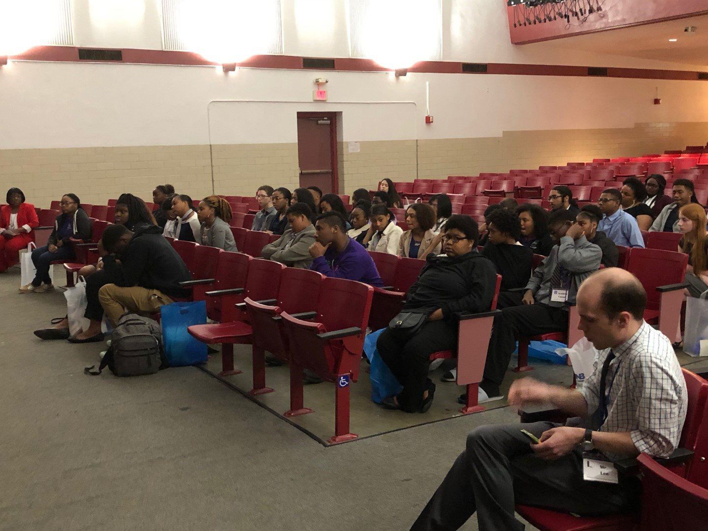 A group of people are sitting in an auditorium watching a presentation
