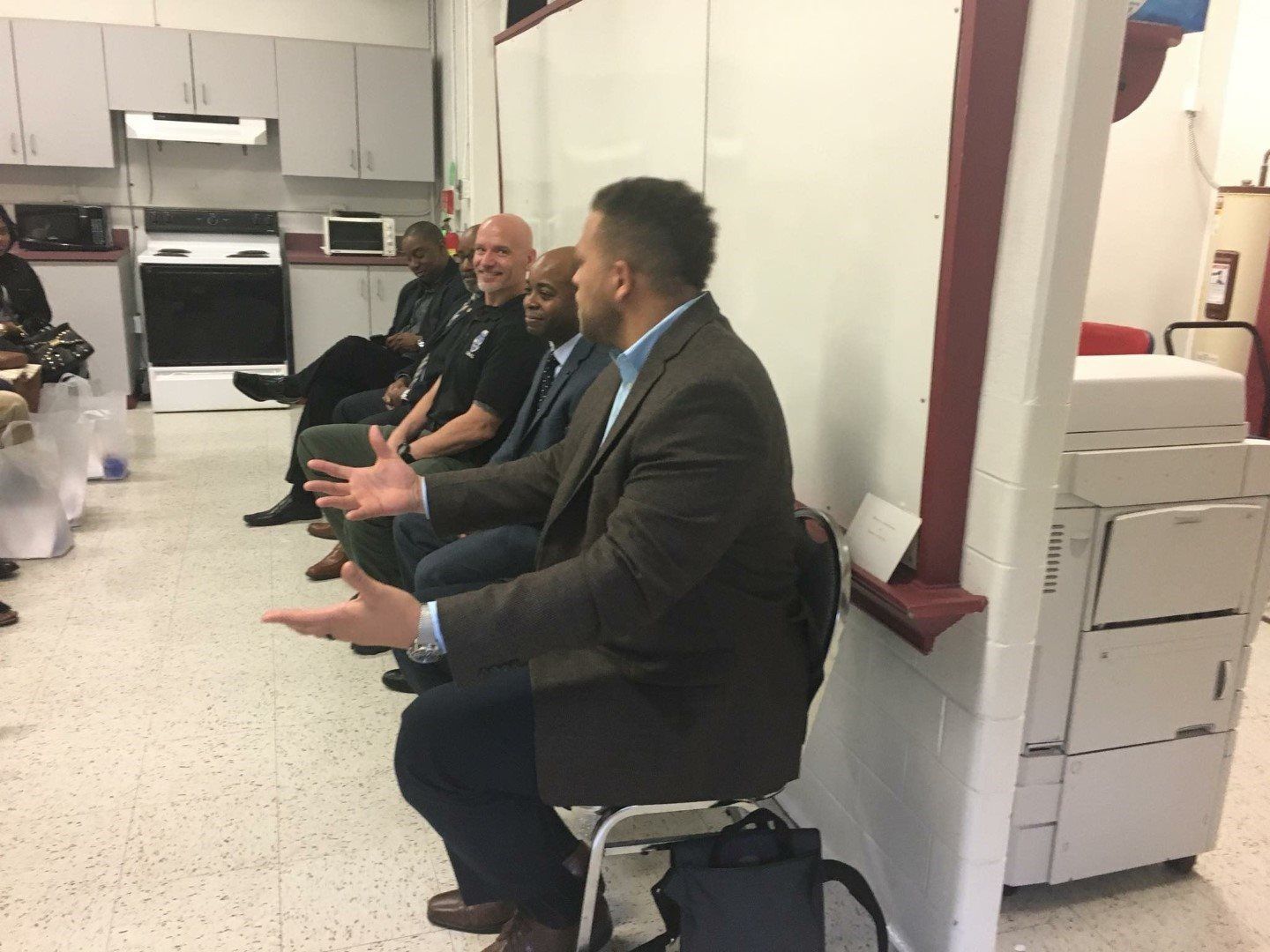 A group of men are sitting in a room talking to each other