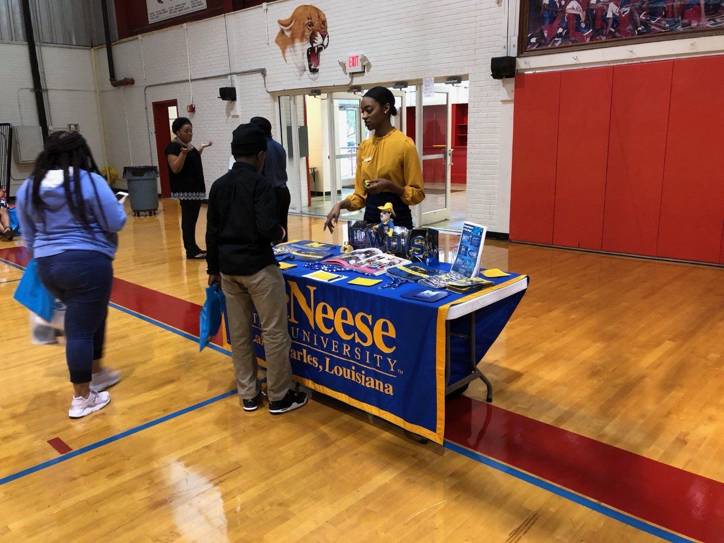 A group of people are standing around a table in a gym.