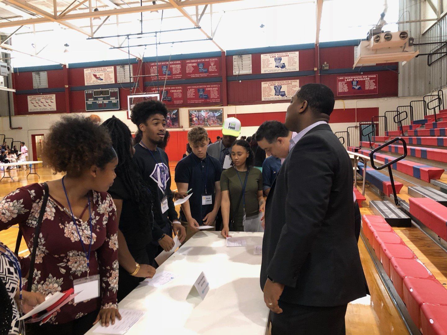 A group of people are standing around a table in a gym.